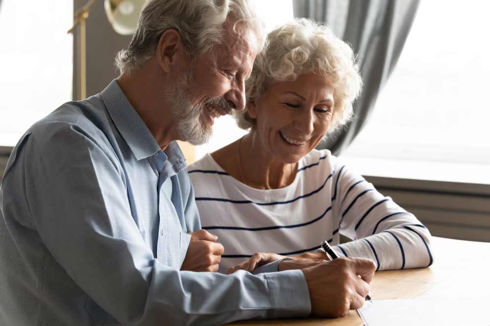 Smiling Senior Couple Signing A Life Insurance Document